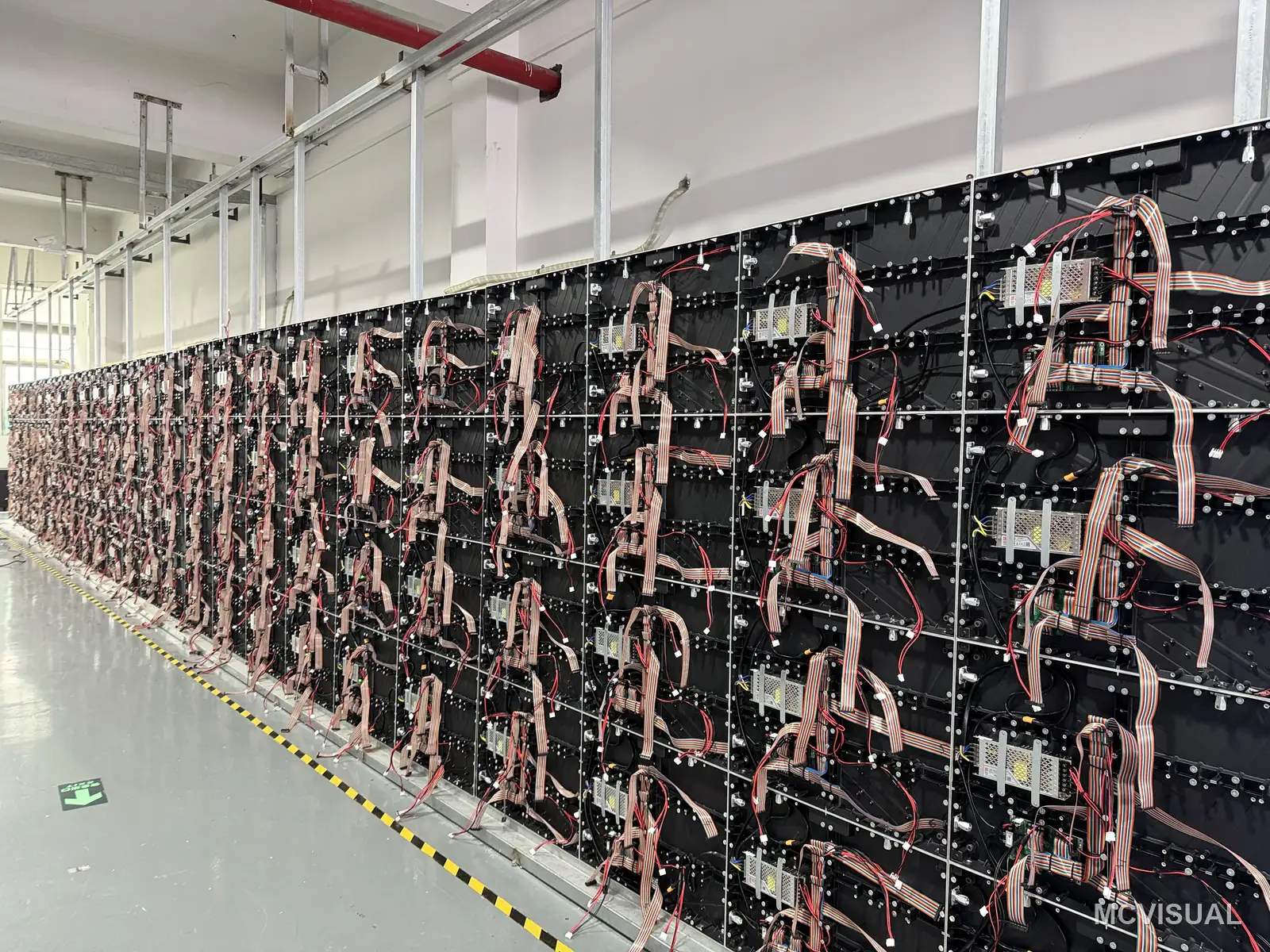 MCVISUAL factory aging bay, Shenzhen, China — Cabinet backs during build-up: power, data and hub-board wiring. Every cabinet in the batch is wired identically so a sp