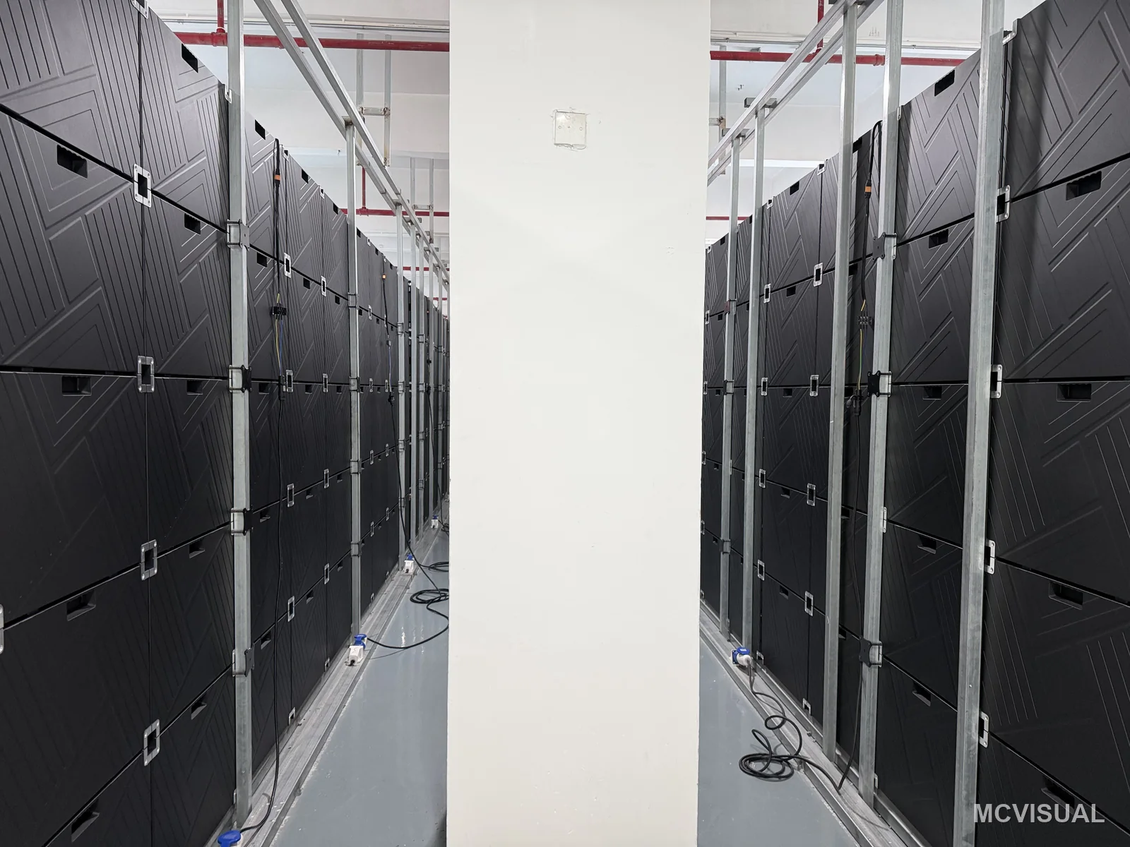 MCVISUAL factory aging bay, Shenzhen, China — The aging bay from the service aisle. 420 cabinets run continuously for 72 hours before any of them are crated — infant