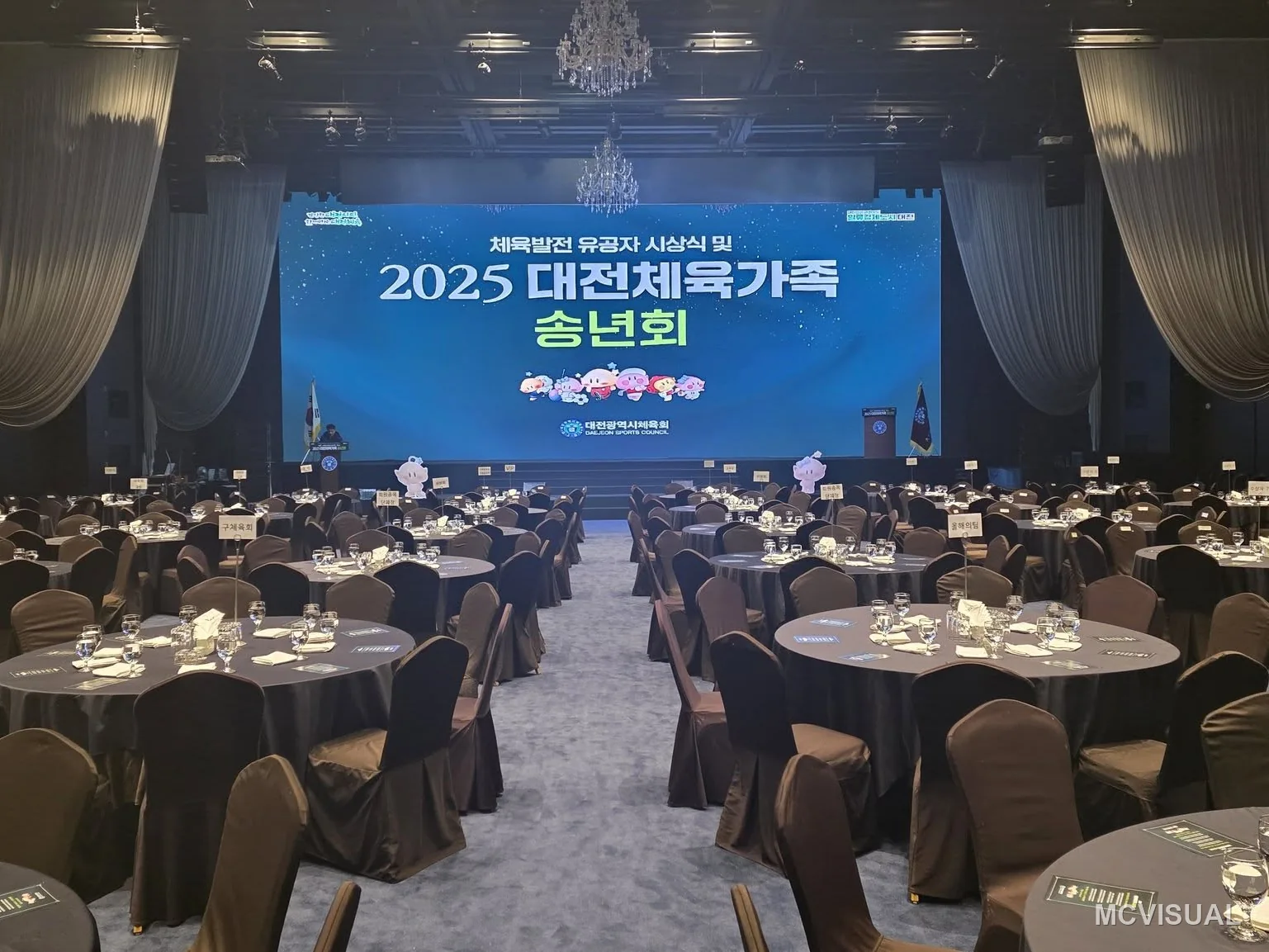 Daejeon banquet and convention hall, Daejeon, South Korea — The same hall dressed for a year-end banquet, round tables replacing the seminar rows. The screen never moves — the room