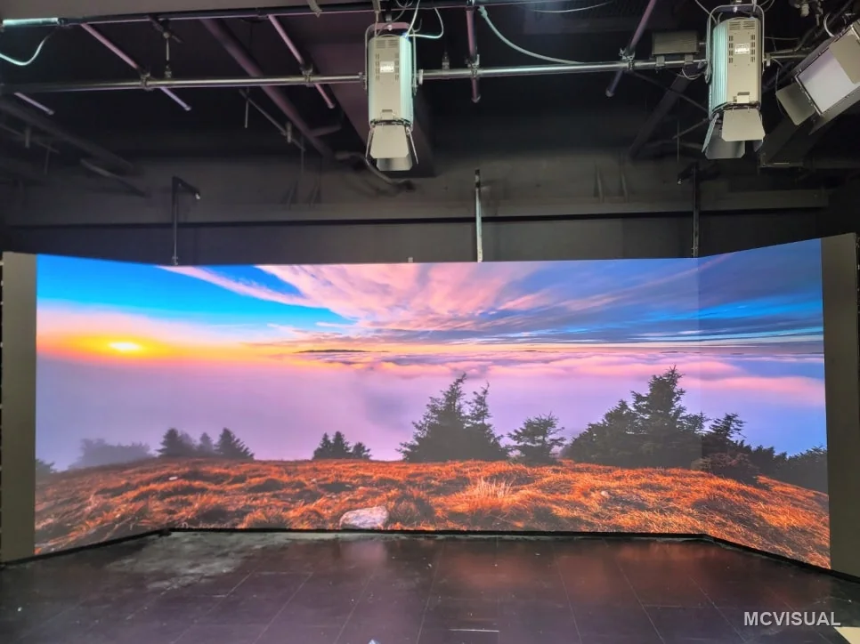 Video production studio, Doksan-dong, Seoul, South Korea — The finished curve lit for a shoot. The arc wraps far enough around the shooting area to fill a wide frame, so the camer