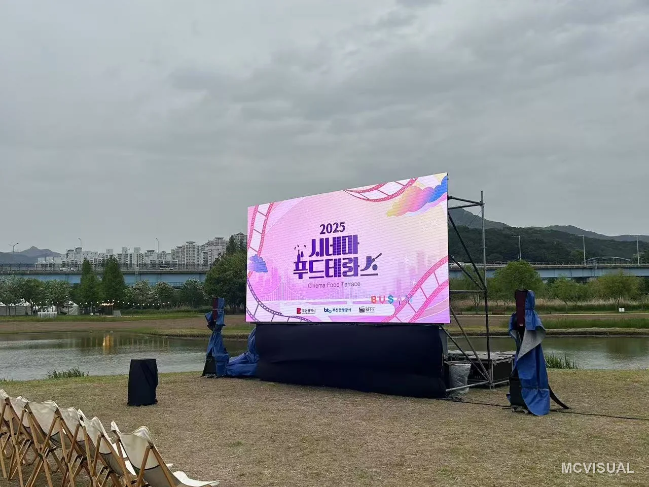 Event rental fleet, South Korea — Twin walls flanking a covered outdoor stage on grass. Ground conditions decide the rig: soft ground means ballast and br