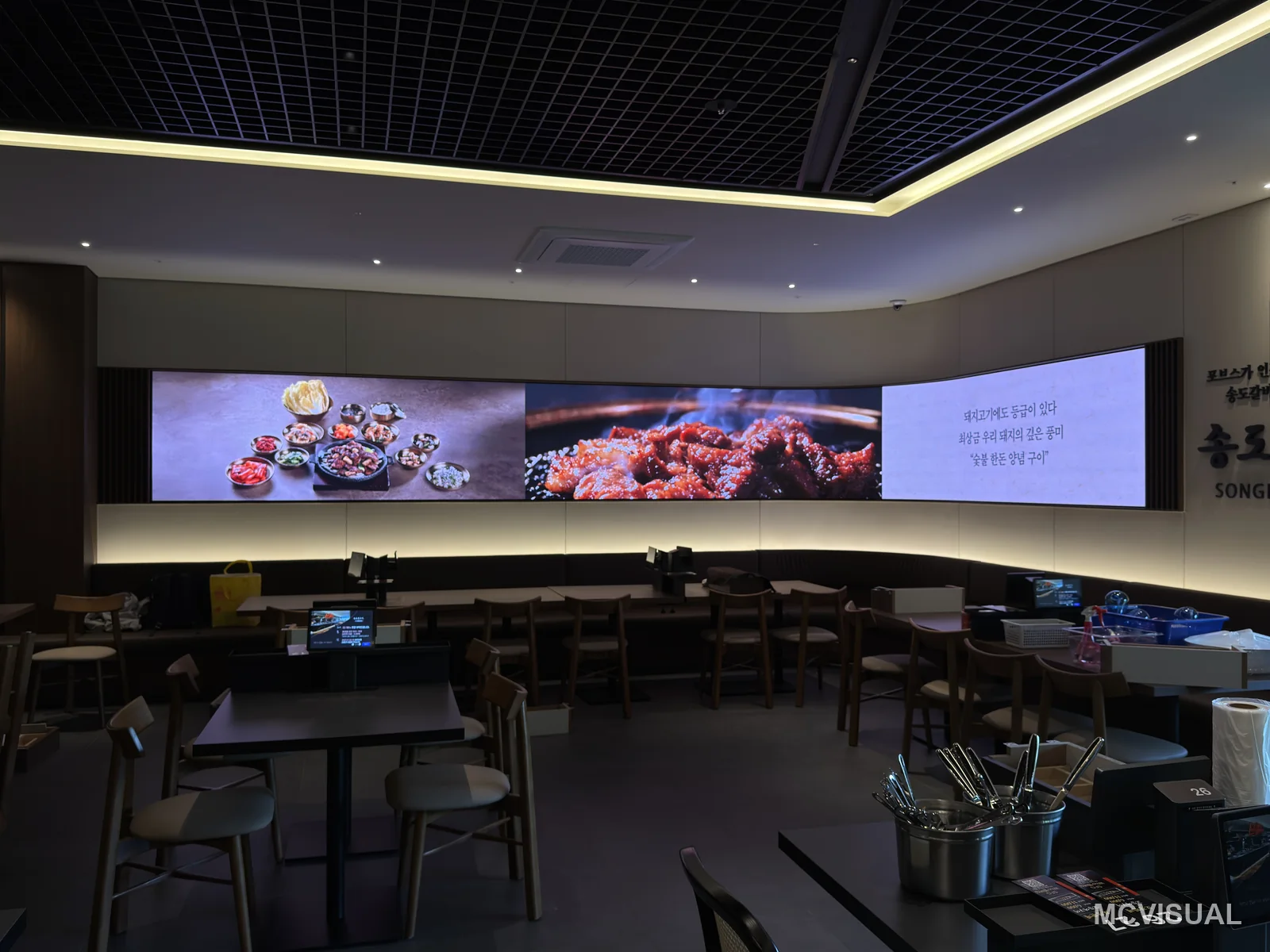 Restaurant dining hall, South Korea — Menu content across the curve at seated eye level. The band sits high enough to clear heads and low enough to read witho